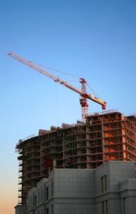 Tower crane on a high-rise building under construction at sunset, showcasing modern urban development.